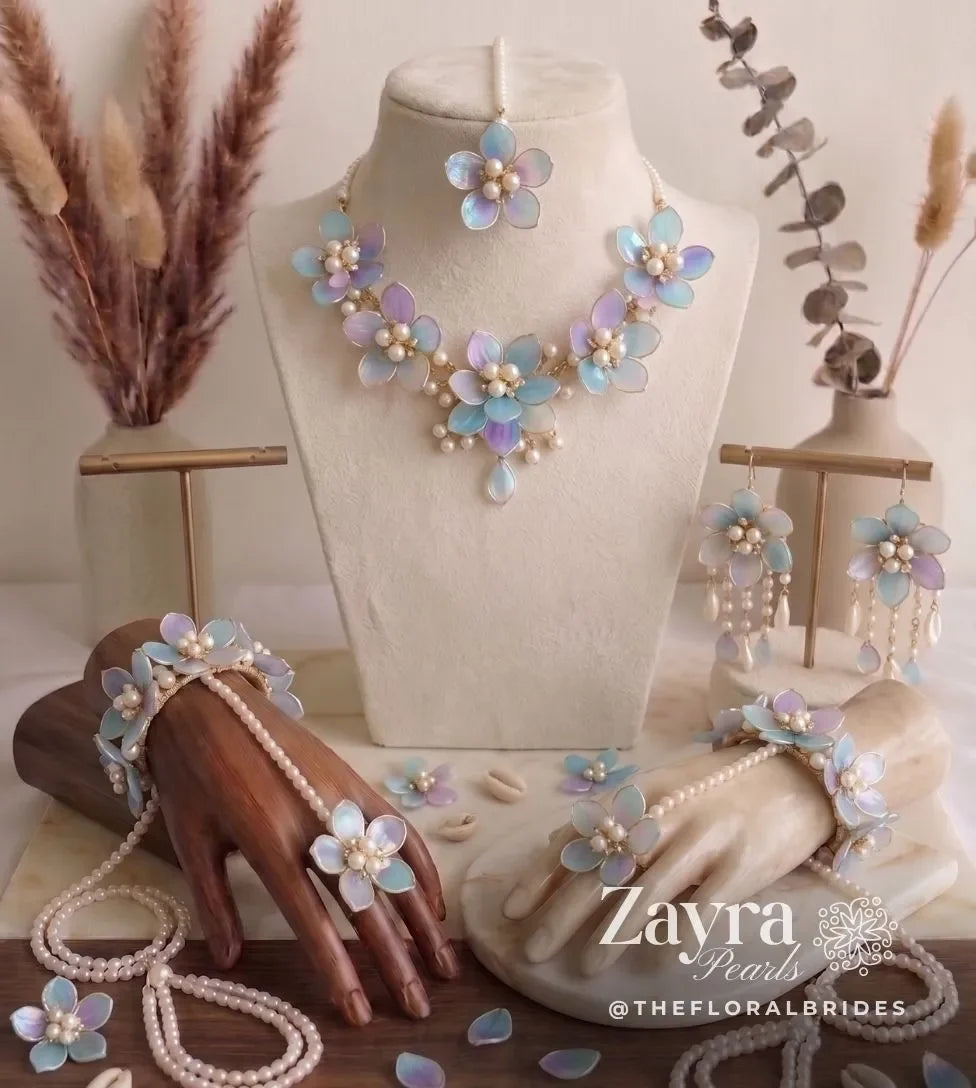 Handcrafted engagement & roka jewellery set by Zayra Pearls, Handcrafted premium pastel blue and purple Resin Carnival Haldi Jewelry set featuring a choker necklace, maang tikka, dangling earrings, and haathphools displayed on luxury busts by zayra pearls