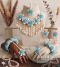 Handcrafted aqua haldi floral set for brides displayed beautifully on a luxury linen background showing the choker necklace, maang tikka, and earrings.
