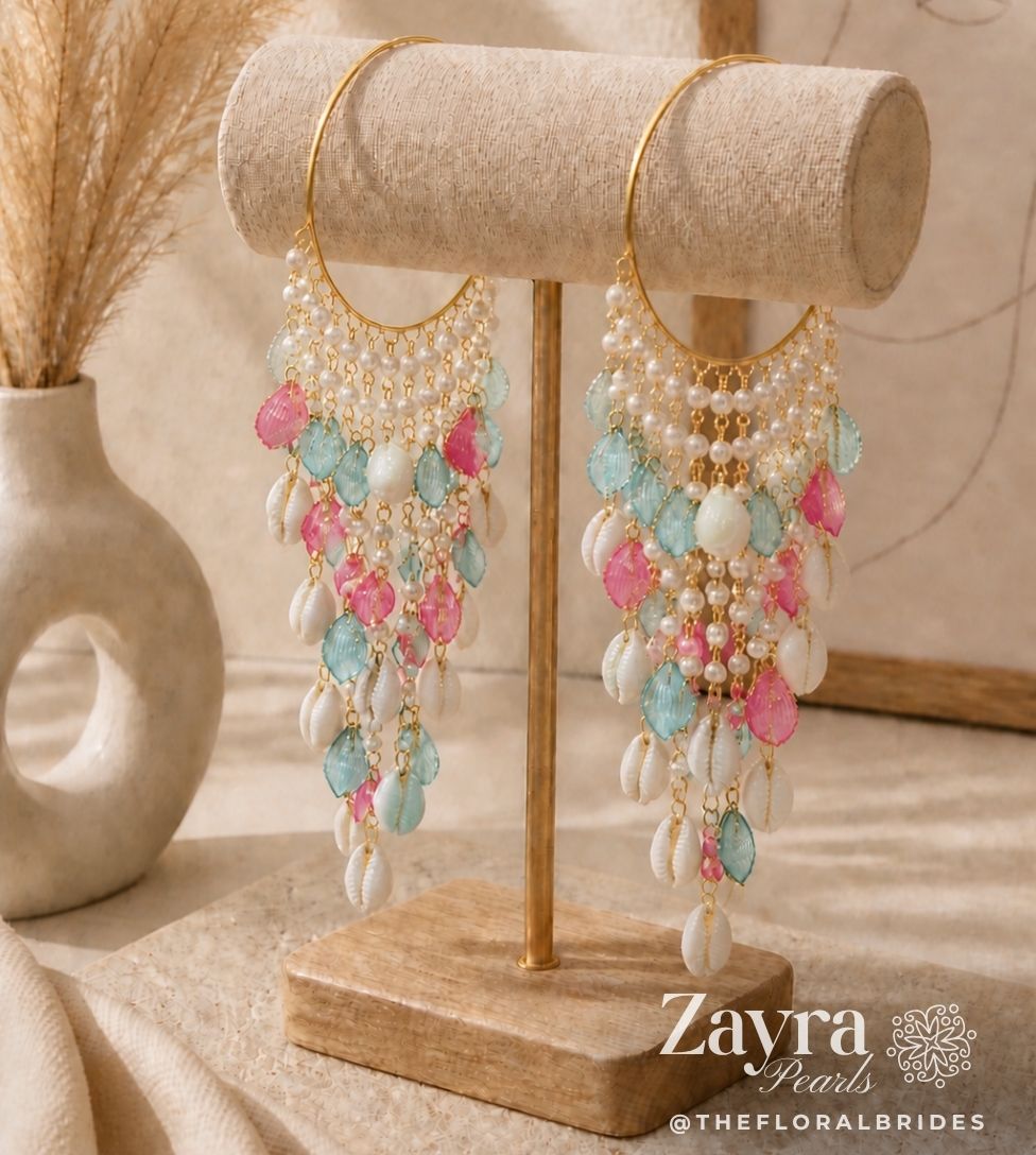 Delicate Sea shell blue pink pastel Haldi Bangles for Bride (Pair) with pink and blue beads on a wooden stand, branded 'Zayra Pearls'.