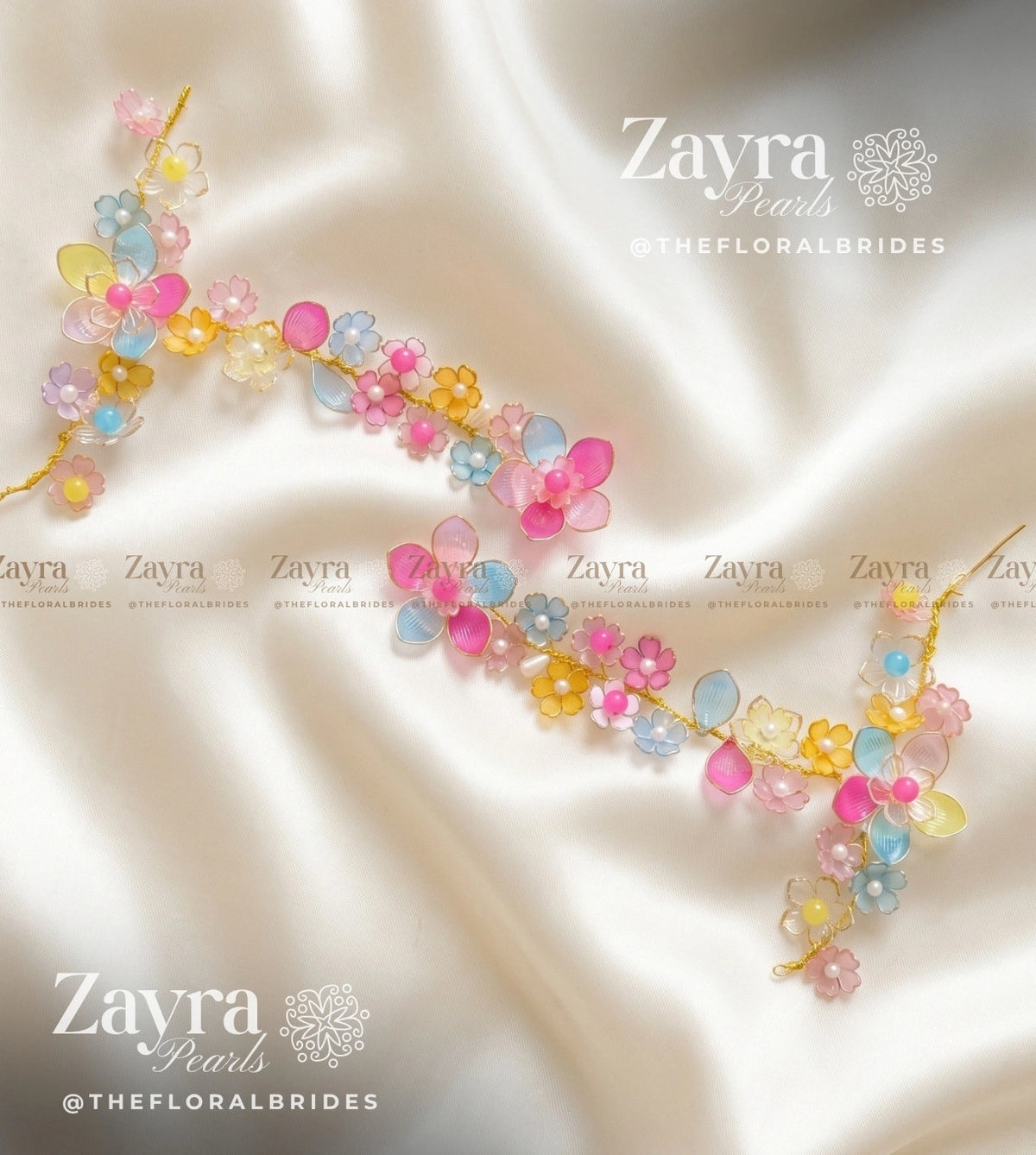 A floral pearl hathphools accessory with pink, yellow, and light blue pearls on a gold chain, displayed on a draped cream satin fabric. The brand name 'Zayra Pearls' is visible as watermarks.