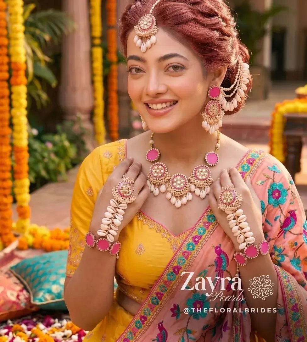Handcrafted lotus pink shell kundan haldi jewelry worn by a smiling bridal model showcasing the choker necklace, earrings, and haathphools.